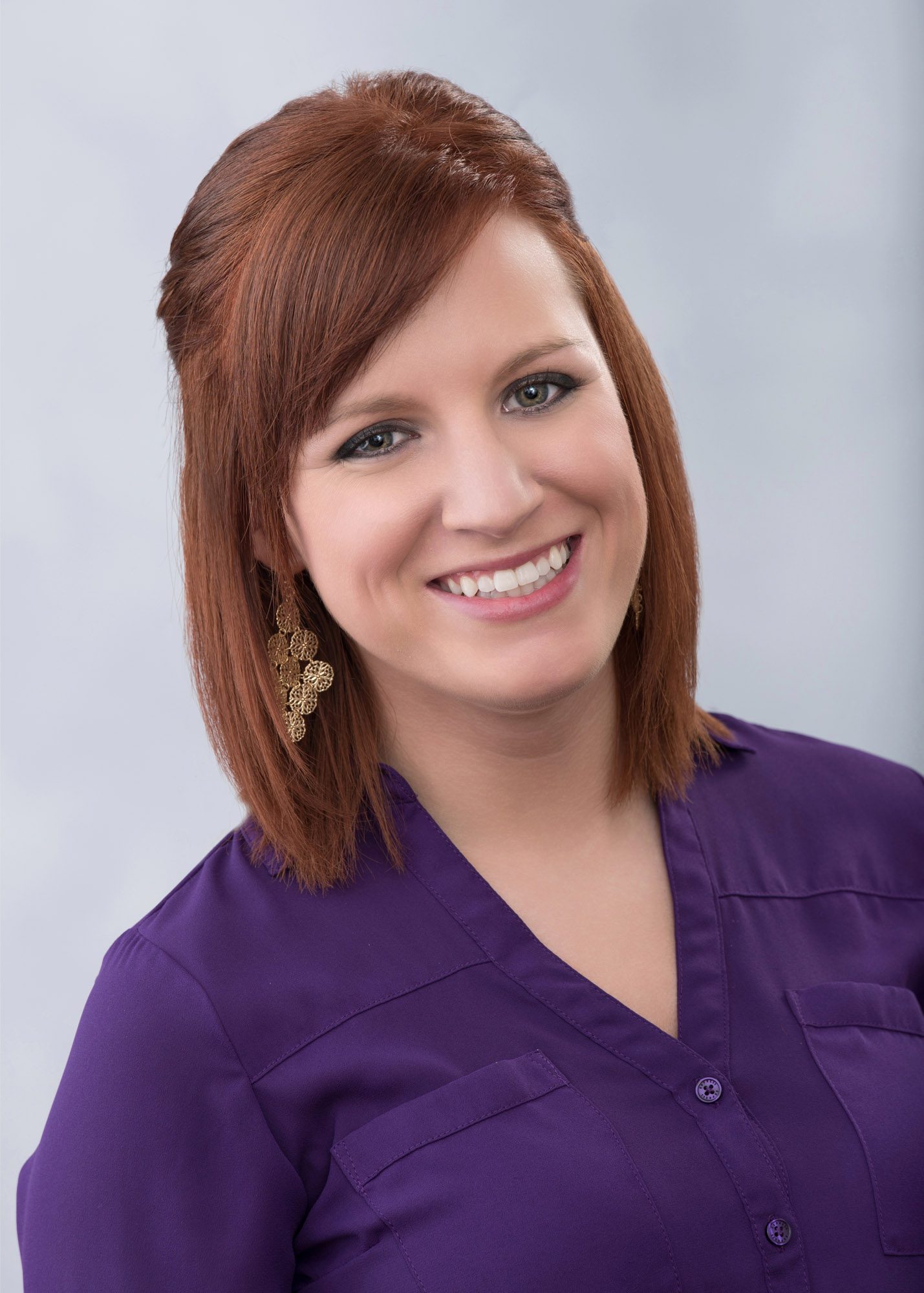 professional headshot of redheaded female with grey background
